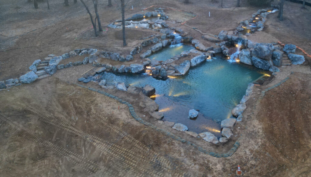 Landscape with illuminated stone-lined ponds and waterfalls.